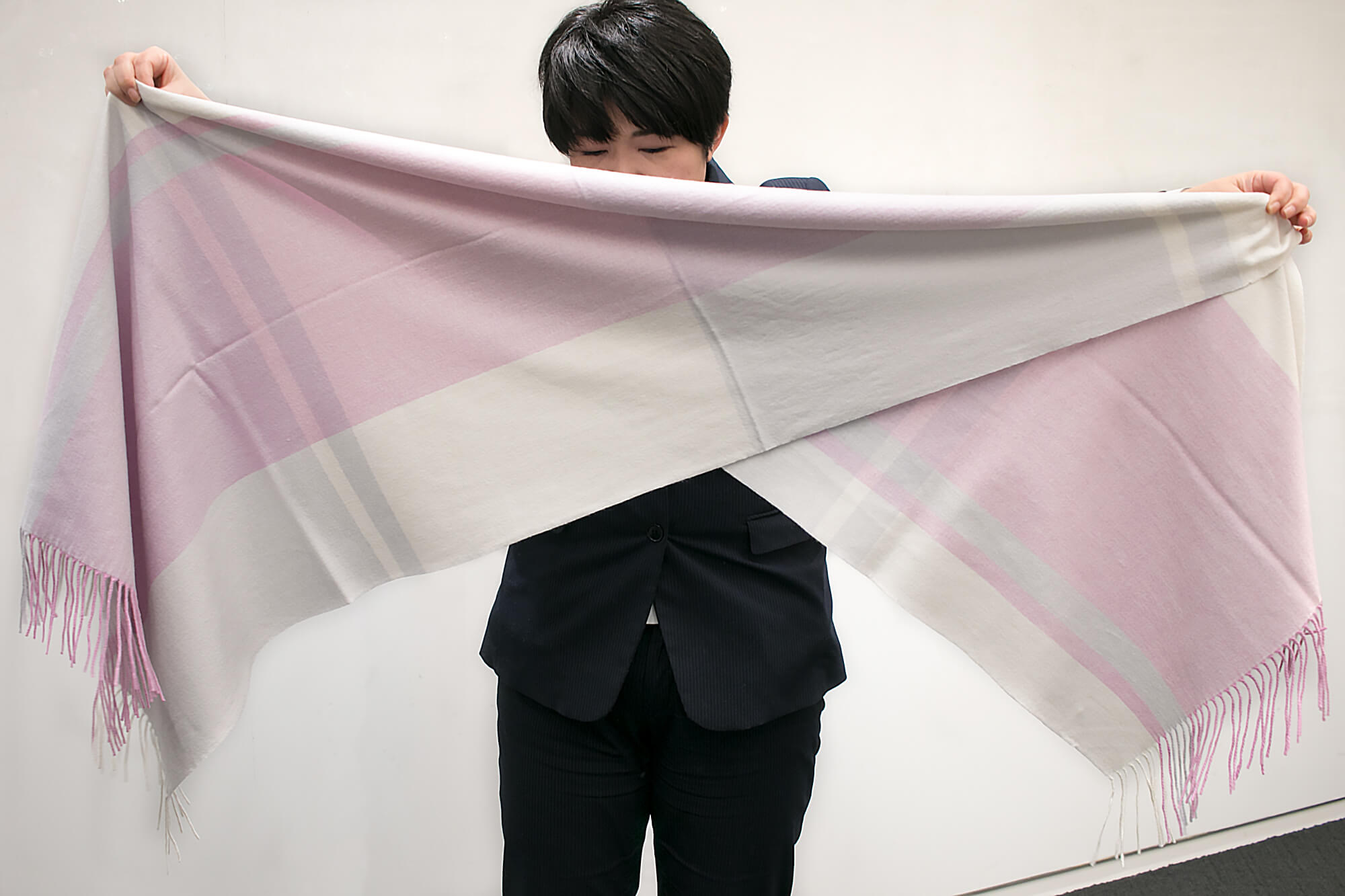 ストールの両脇を対角に1/3の辺りを持ち、中心から二等辺三角形ができるように折ります