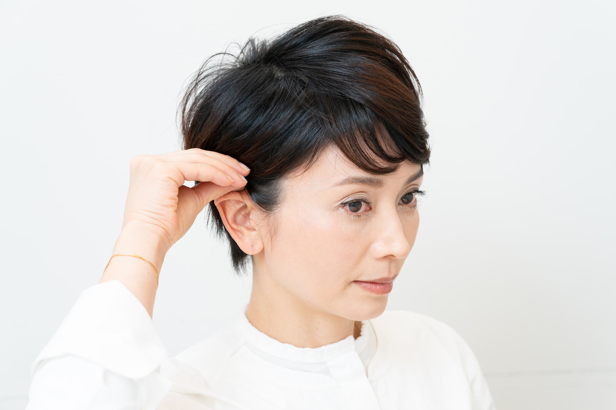 ワックスをつけた指でなでつけるように、サイドの髪を耳にかける。