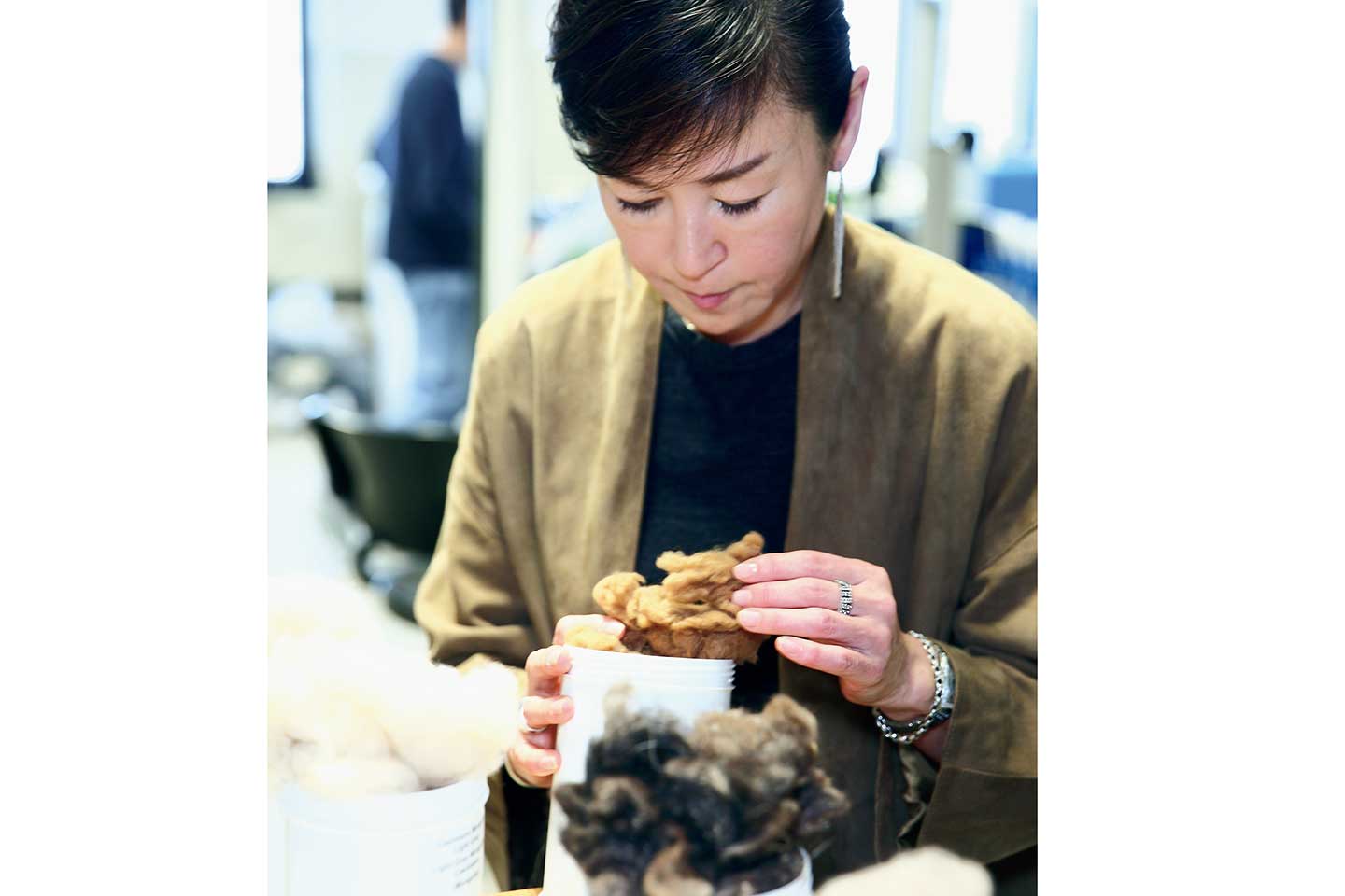 貴重なビキューナの原毛を手に取る戸野塚さん。