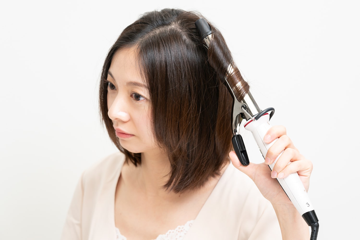 毛束の中間からアイロンに内巻きに巻き付け、3秒後に斜め下におろす。