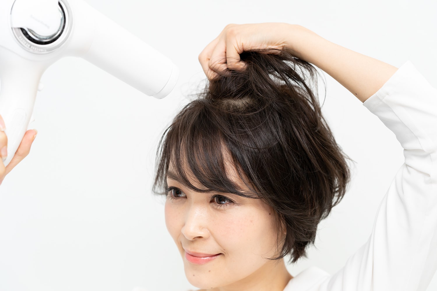 熱風の力で頭頂部の髪の根元が立ち上がるように、垂直につまみ上げること。