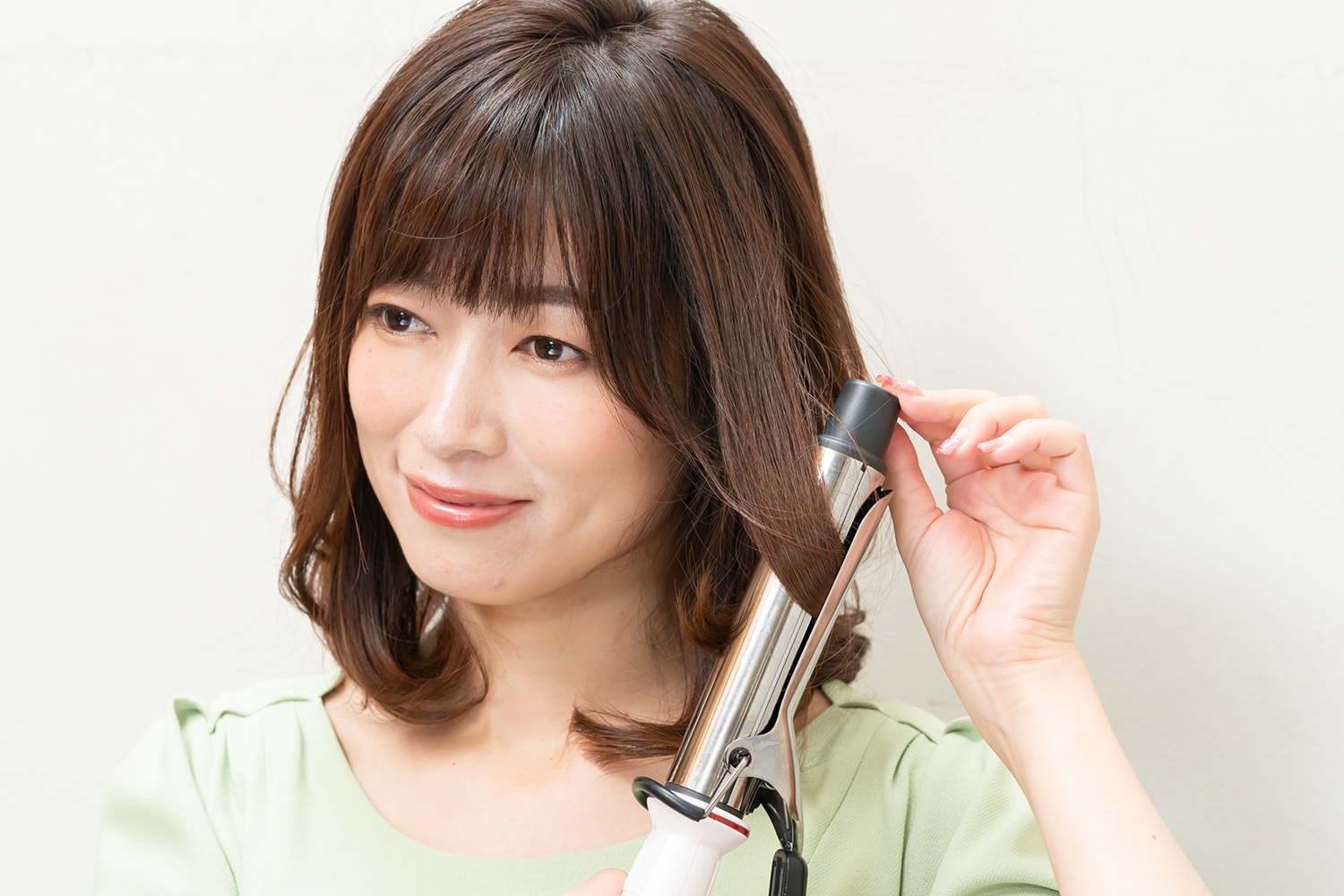 顔周りの髪は外巻きに。毛束の中間から毛先までを巻く。