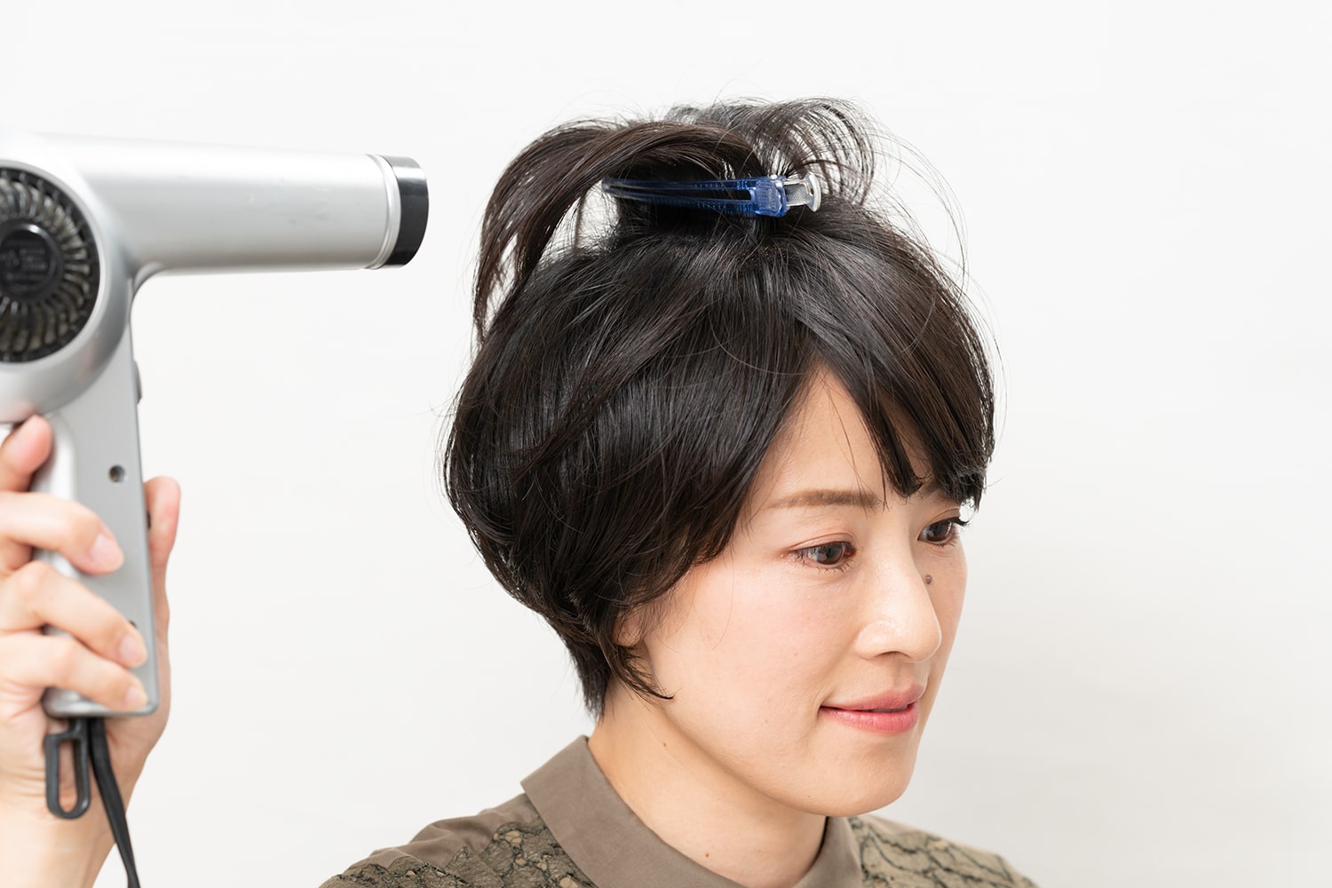 トップの髪を立たせるようにピンではさみ、ドライヤーを弱風にしてあてる。10秒経ったらドライヤーを止め、1~2秒後にピンを外す。