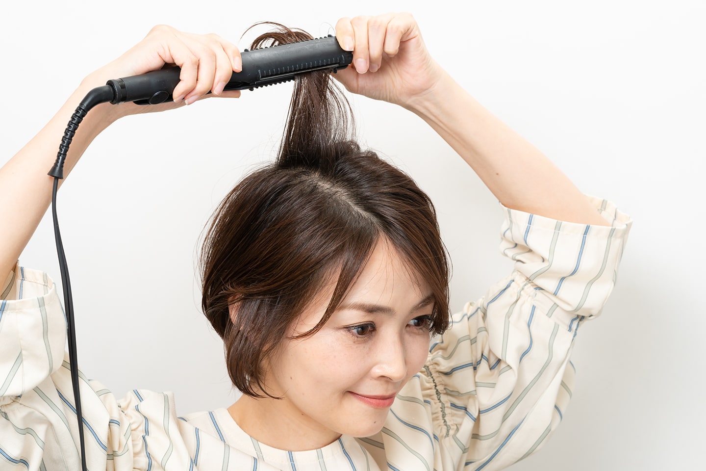 毛束を真上に持ち上げ毛先だけ内巻きになるようにストレートアイロンを通す。