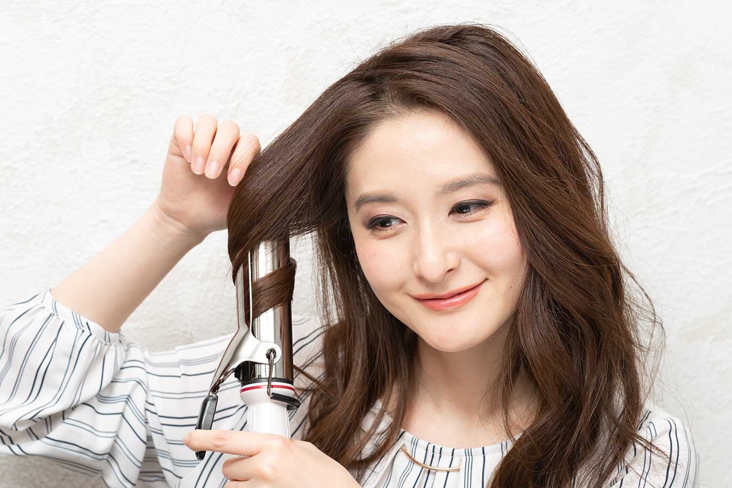 コテは36mmを使用。耳前の毛束をまとめて中間だけを巻く。逆サイドも同様に。