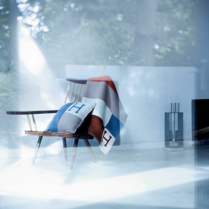 ブランケット［135×175㎝］￥378,000・クッション［43×43㎝］￥126,000・左ページのニット￥215,000（エルメスジャポン）