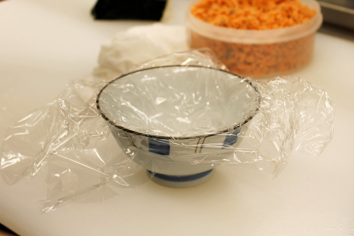 茶碗やお椀にラップをのせてくぼませます。ラップを使うとご飯の扱いも簡単で、具も入れやすいのだとか
