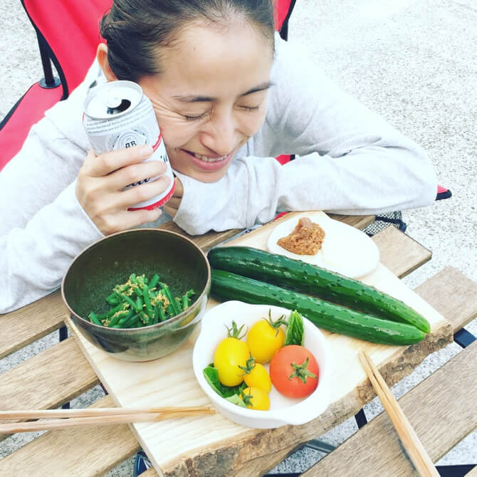 採れた野菜を前に、ビールを飲む堀江さん