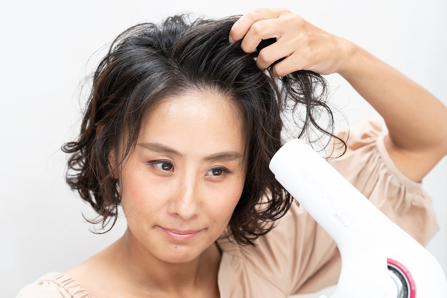 前髪とフロントの髪を持ち上げたら、根元に熱風を当てて髪を立たせる。