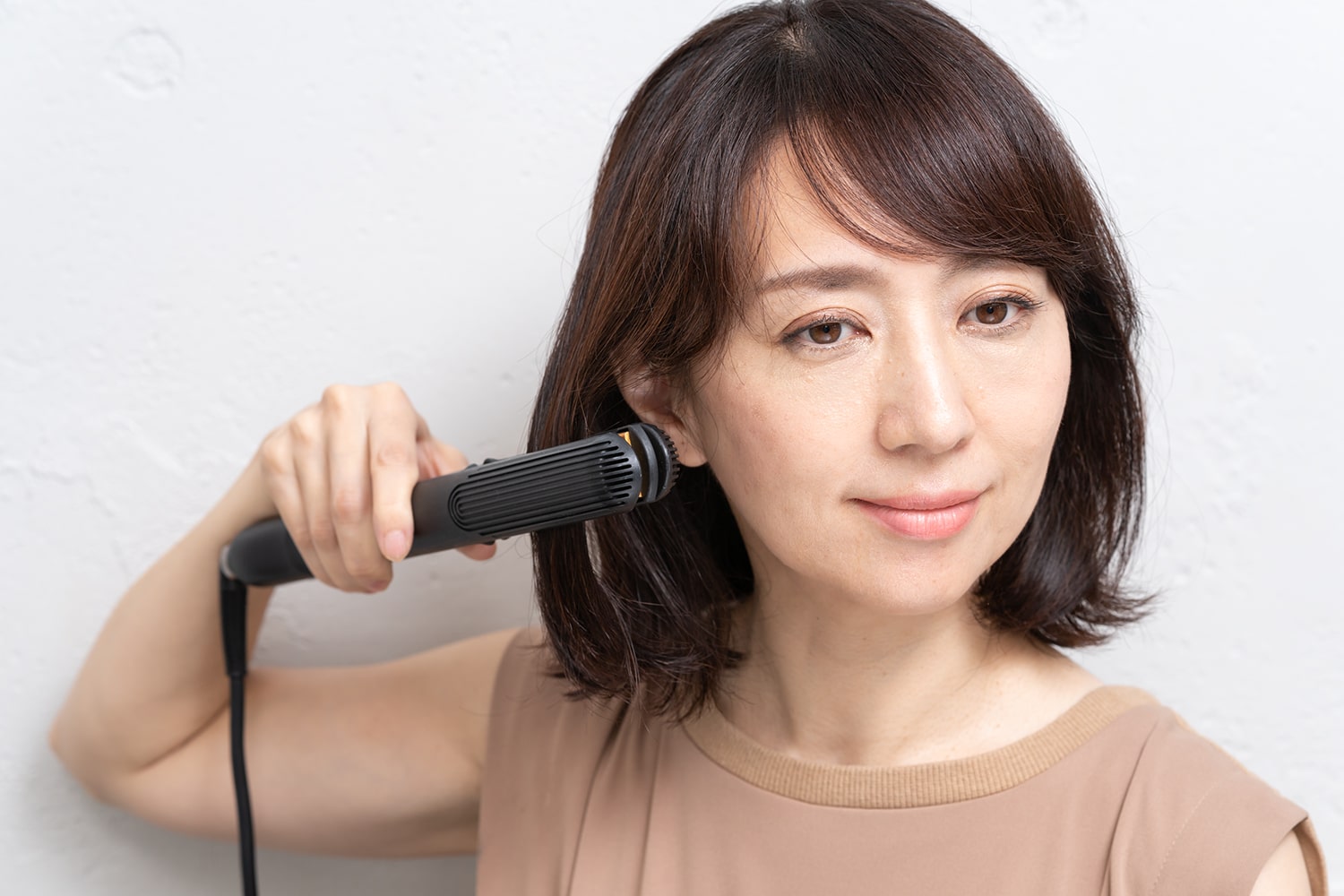 レイヤーの入った短い髪をアイロンに挟んだら、そのまま下ろすように通す。