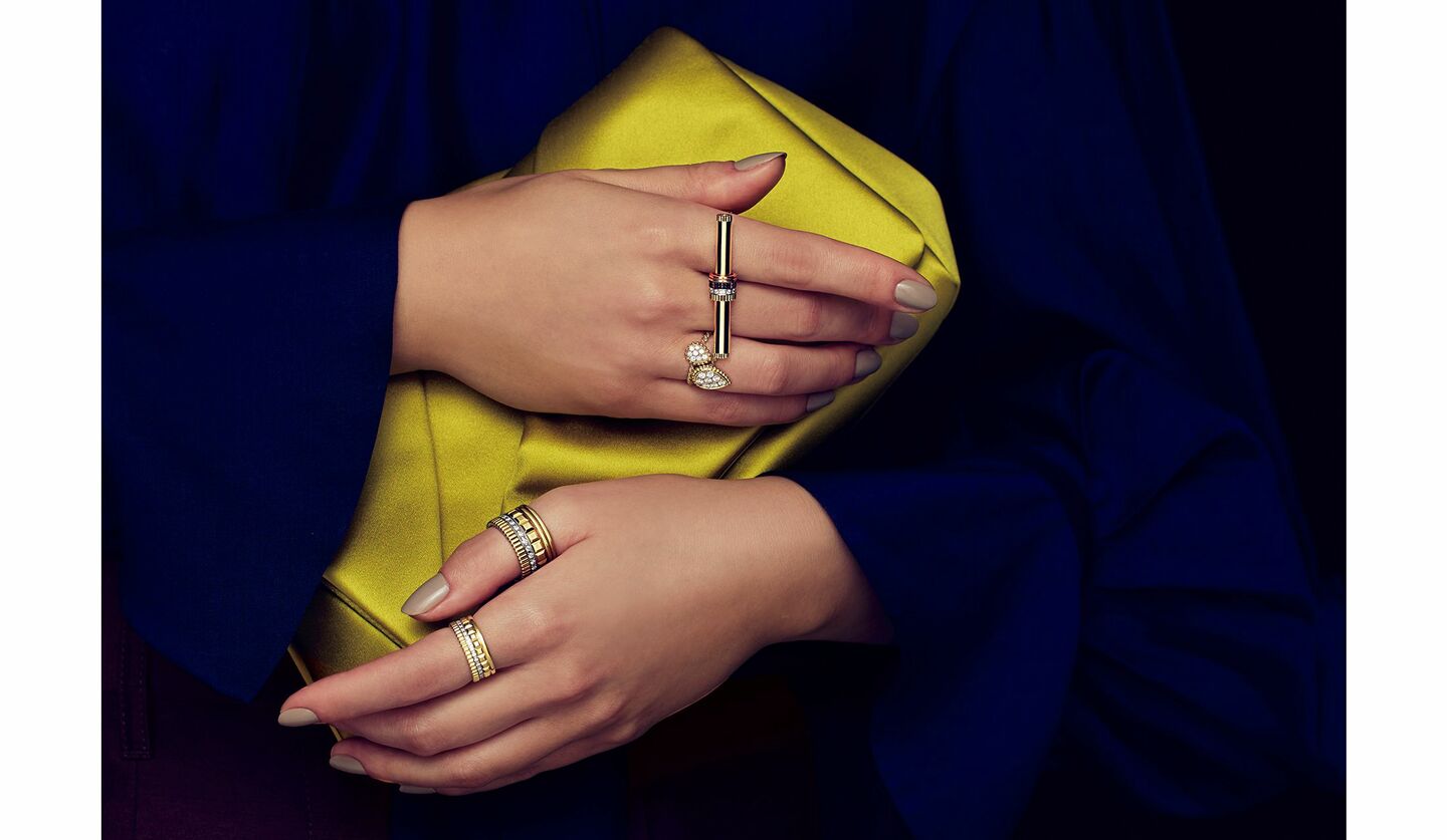 「ロド」のクラッチバッグと「ブシュロン」のジュエリーを纏った女性の手元