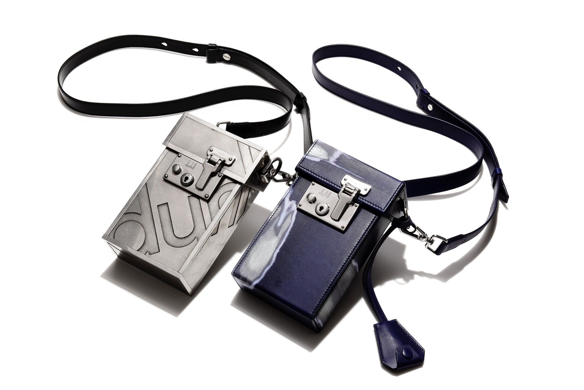 左/THE LOCK BAG AD シルバー¥573,100 4つのレーザーカットパネルを手作業で組み立てたメタル製。右/THE LOCK BAG アブレイジョン インディゴ ¥278,300 ボックスカーフレザーを使用。ストアの壁面装飾にもなっているブランド独自のデザイン「アブレイジョン」柄。サイズ共通:W10.5×H17×D5.5cm (ダンヒル)