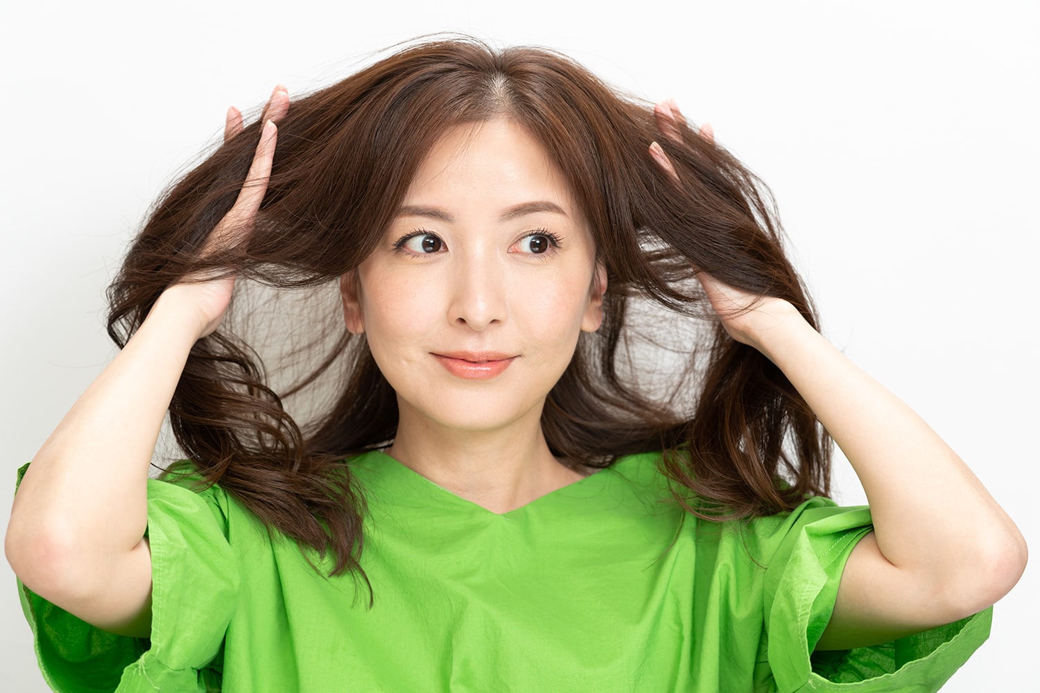 カールアイロンで巻いたら、カールした毛束をほぐすようにかき上げる。