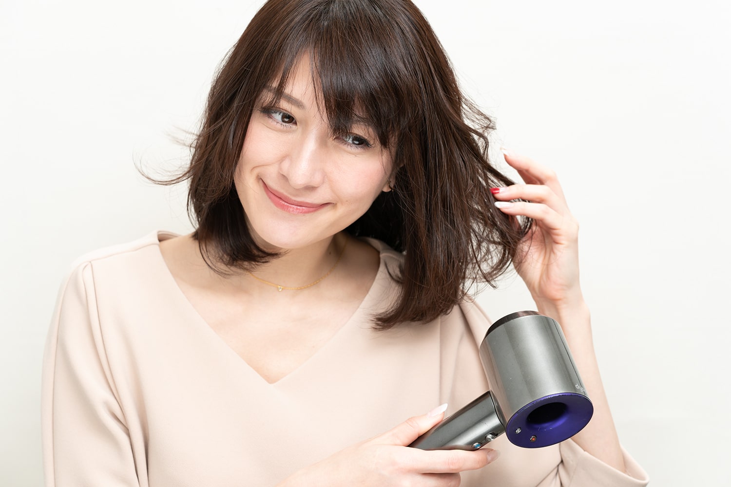 仕上げに巻いた毛束を冷風でほぐす。熱風は巻きが取れるので冷風で髪を散らすようにほぐすのがポイント。巻いているような、いないような、ニュアンスのあるスタイルに仕上がる。