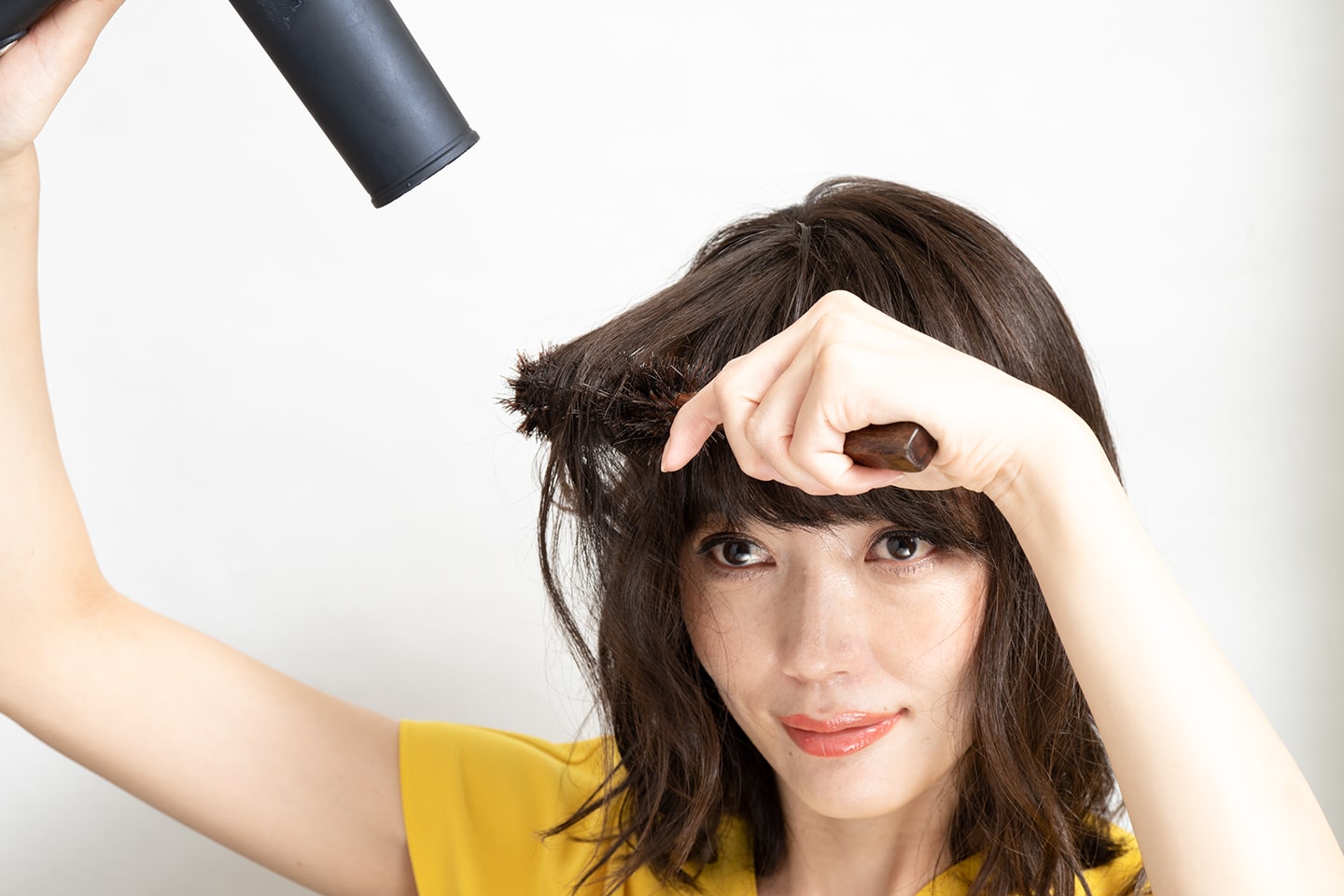 こめかみより上の髪を髪の中間から毛先にかけてロールブラシで内巻きにし、根元を伸ばすようにドライヤーをあてる。