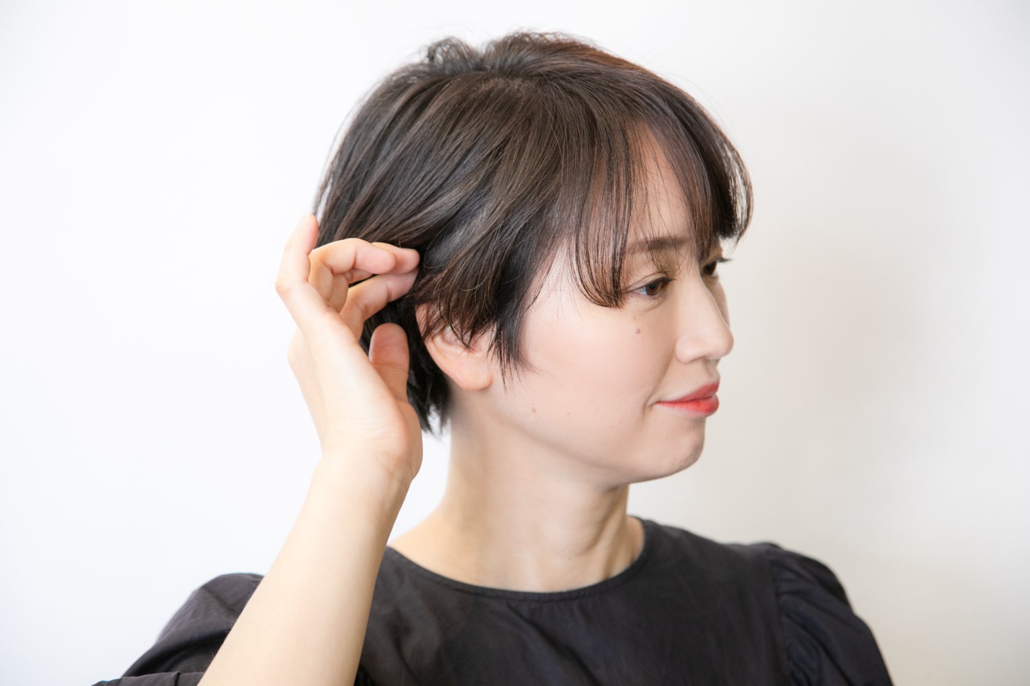 サイドの髪を耳にかけ、前髪を流して全体のかたちを整える。