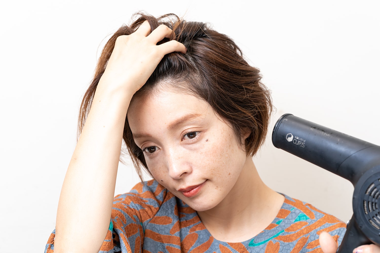 普段の分け目とは逆に髪をかき上げてドライヤーを当てる。