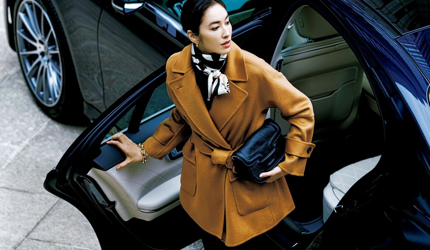 車から降りようとする、キャメルのカシミアコートを着用したモデル