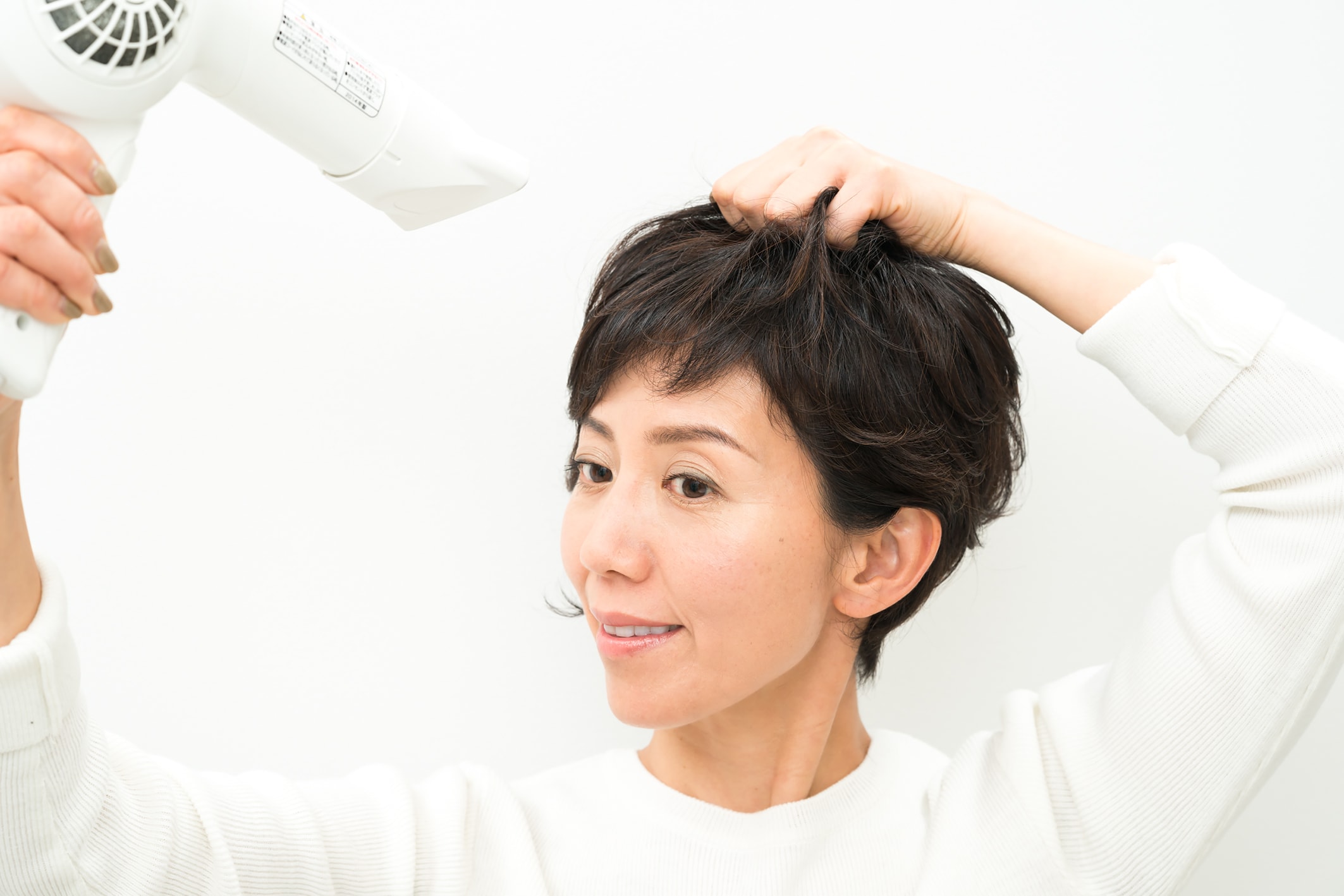 毛束を片手で握りながら、ドライヤーをあてる