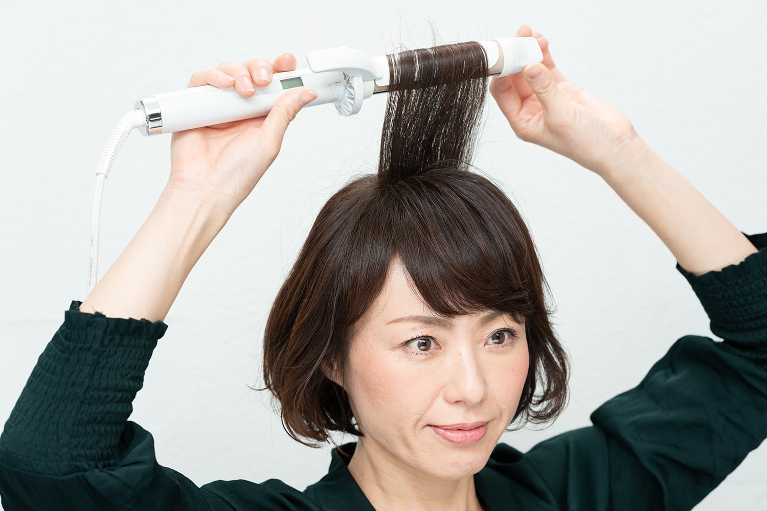 髪の根元を立たせるように、毛束を垂直に持ち上げながら毛先を巻くこと。