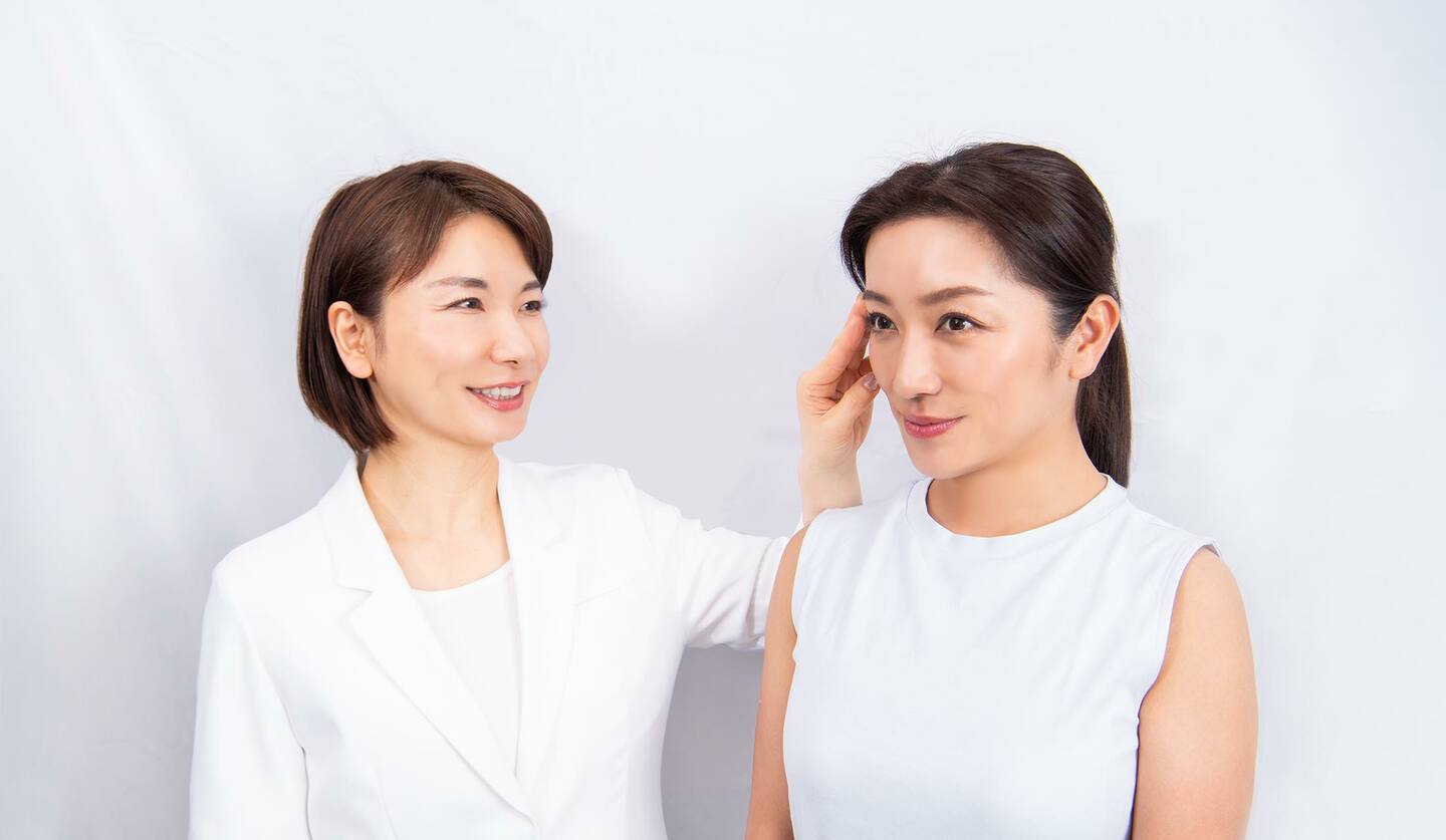 並んでいる二人の女性　ツボ押しの指導をしている