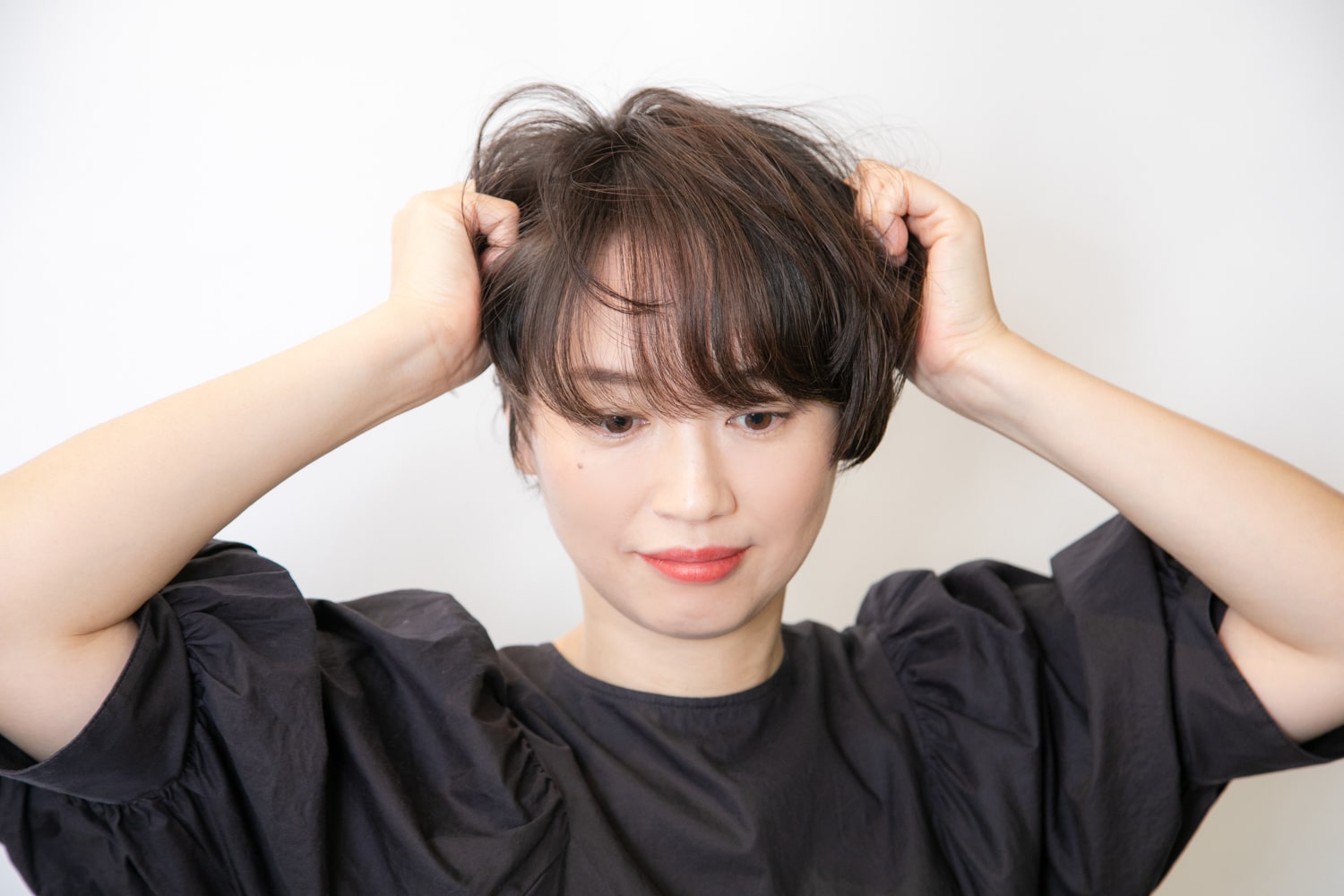 ファイバーワックスを適量手のひらにとって伸ばし、毛束を握るようにして全体になじませる。