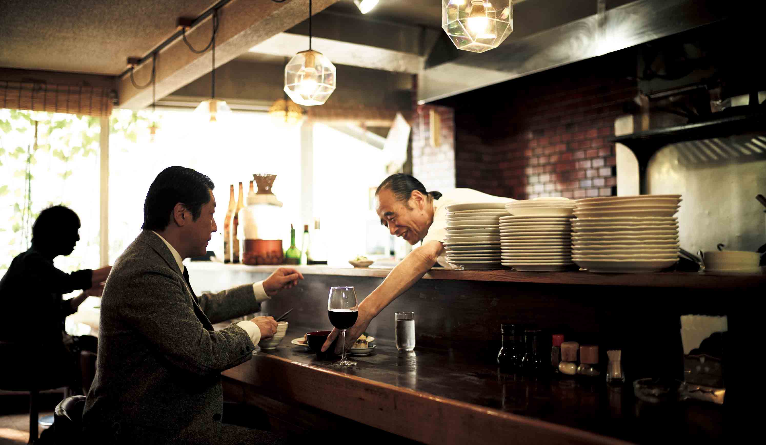 池波正太郎を彷彿とさせる、ツイードの3ピースで来店した山本氏。店の雰囲気ともよく調和している。右はご主人の大木氏。写真のとおりの優しい笑顔で、いつも山本氏を出迎えている。「Ohki」東京都渋谷区渋谷1-24-7 渋谷フラットビル2F TEL:03-3409-2750 営業時間/11:30~20:30、土曜・日曜・祝日11:30~15:00 不定休
