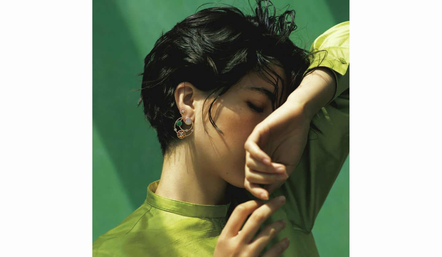 ディオールのグリーンのサテンシャツにスパイラルフープのピアスをしたショートカットの女性の写真