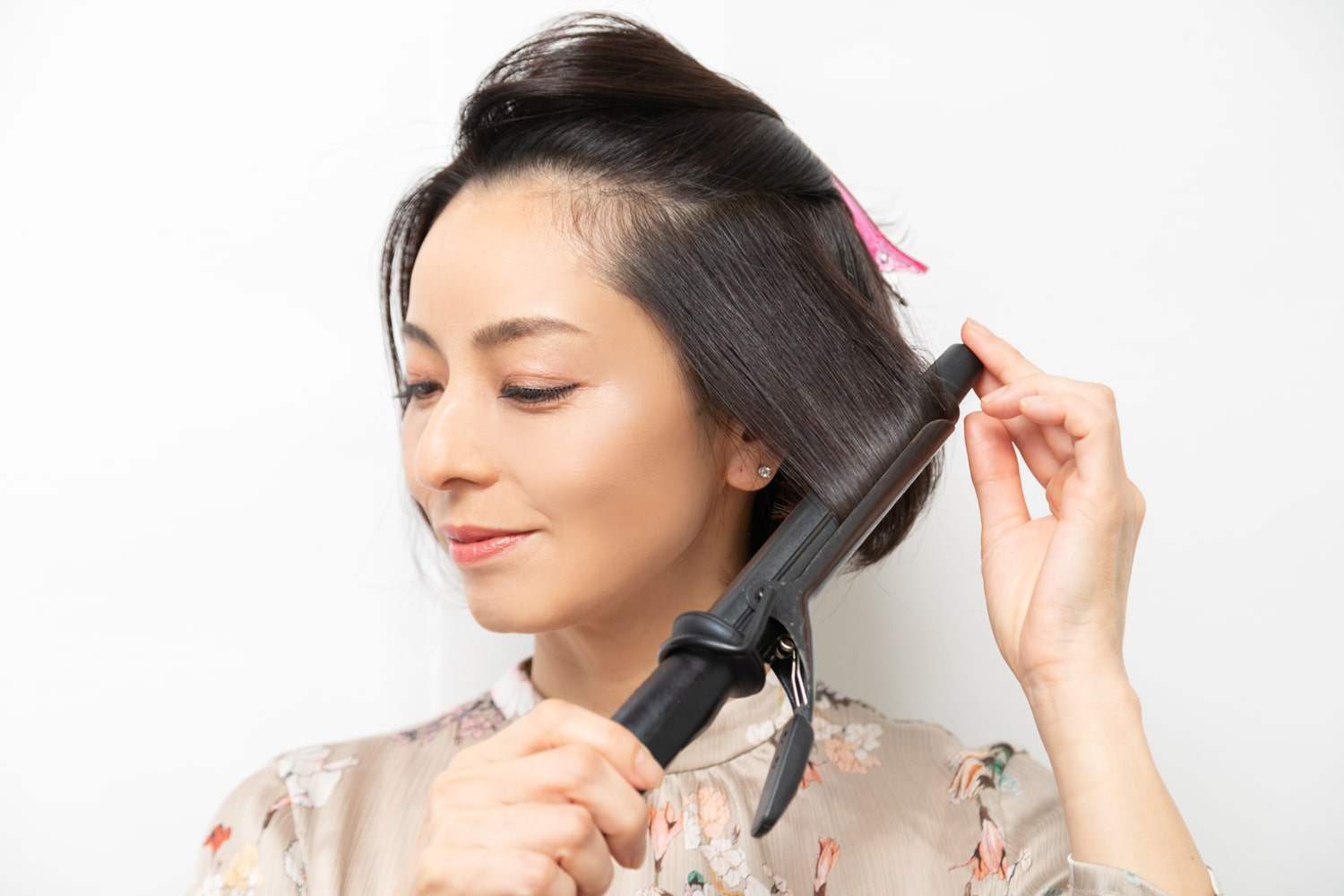 サイドの髪を上下2段に分ける。26mmのヘアアイロンで、下段の髪を毛先から1回転内巻きに。