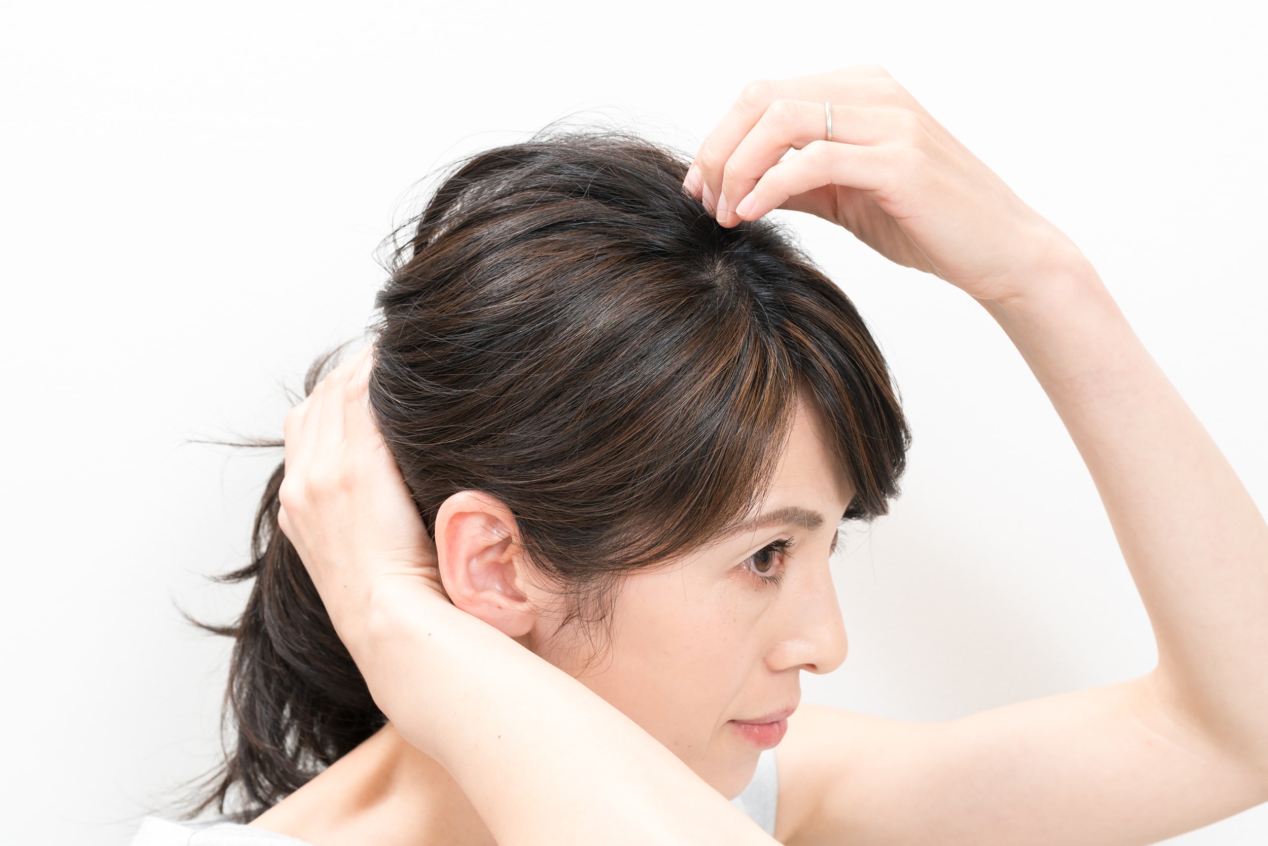 片手で束ねたゴムを抑えながら、頭頂部から2~3㎜ずつ毛束をつまんで引き出す。鏡を見て中央がいちばん高くなるようにすること。