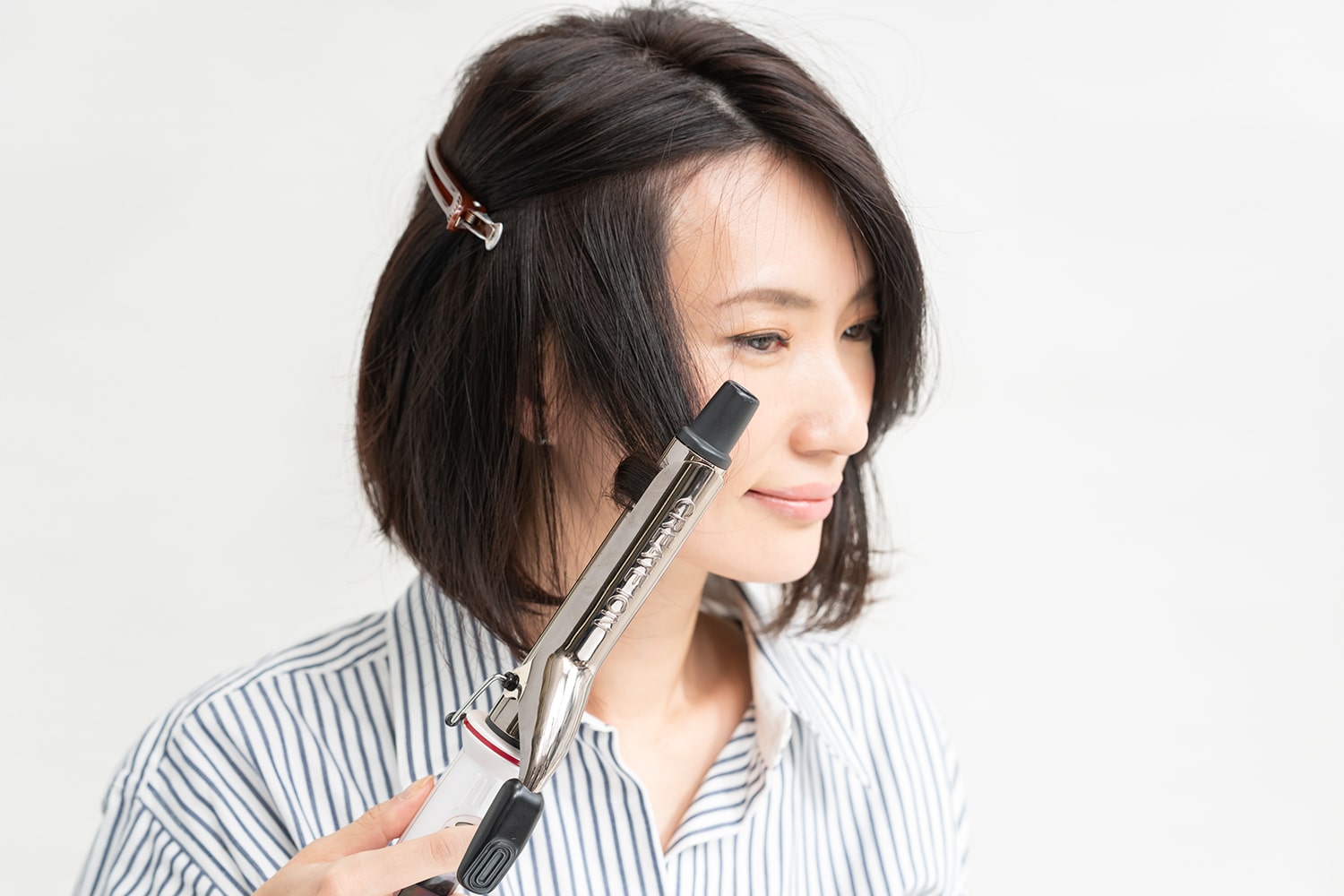 アイロンは26mmを使用。ざっくりと毛束をとって、中間から毛先に向けてアイロンを滑らせるように巻く。顔まわりは外巻き、次の束は内巻きと、交互に巻くのがコツ。表面の髪を留めておくとやりやすい。