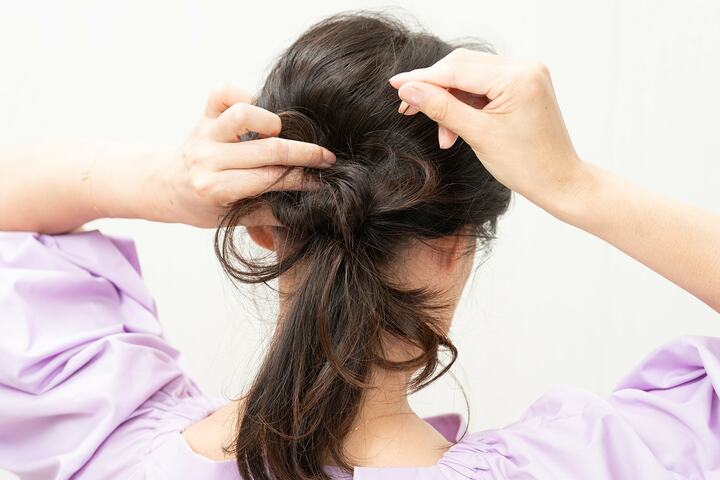 毛束をねじり、毛先をゴムの根元にピンで固定。毛束は２〜３つに分けて、数回繰り返す。