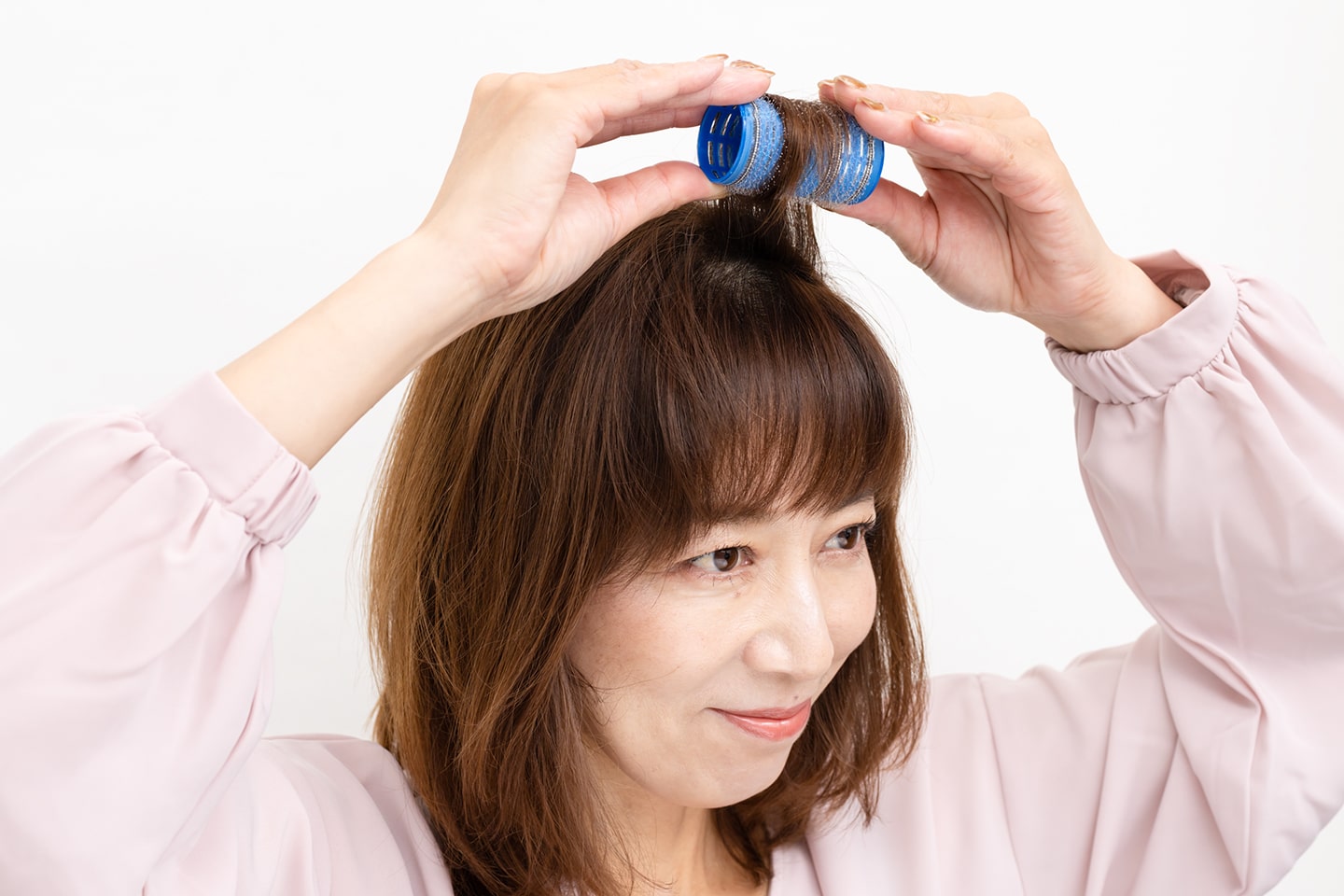 根元を立ち上げるように毛束を引き上げながら毛先から巻く。