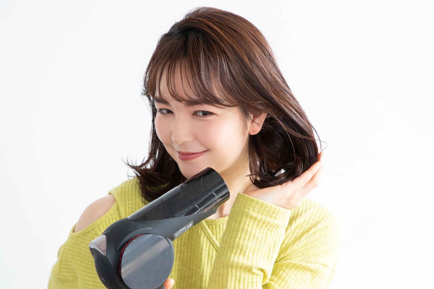 髪を下から持ち上げるように手のひらにまとめ、ドライヤーの風を当てて乾かしカールを出す。