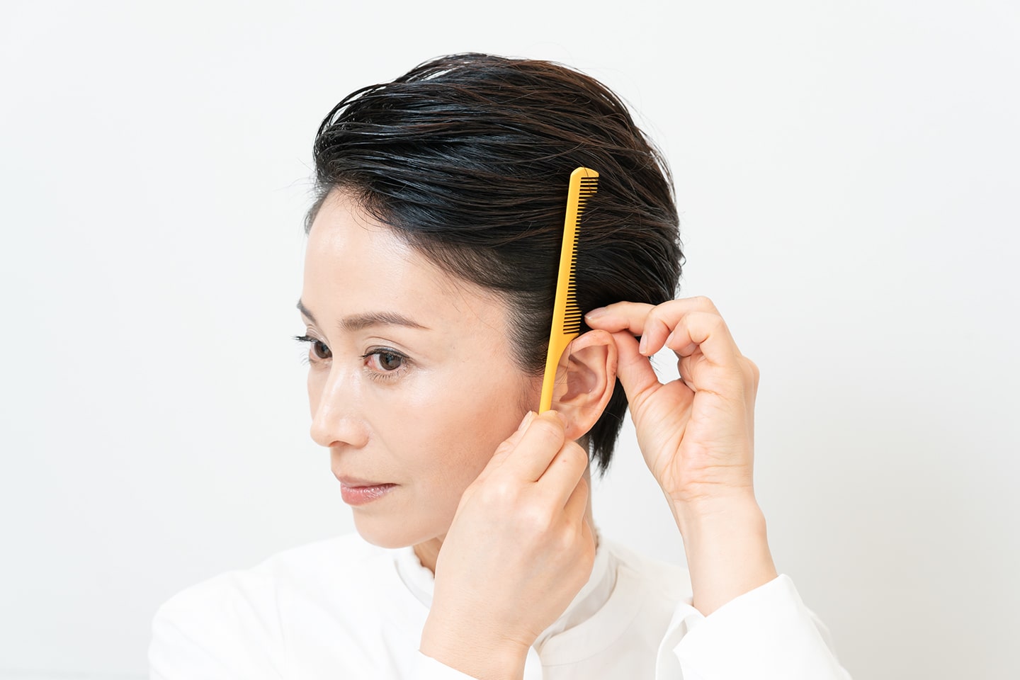 サイドの髪を耳にかけながらタイトにまとめる