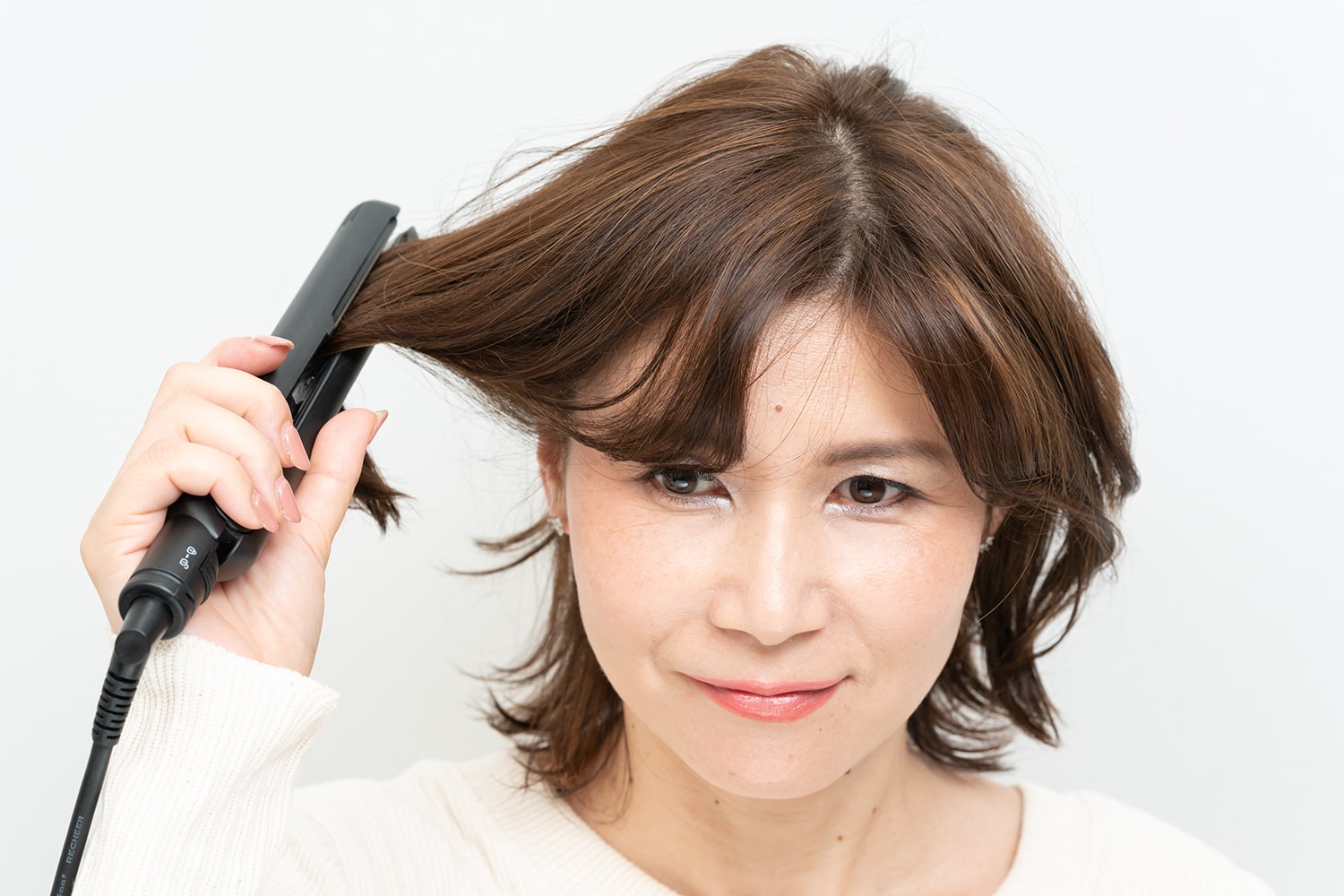 下に引っ張るのではなく、持ち上げながら内巻きに。ブローするようなイメージでアイロンを当てると◎。逆サイドも同様に。