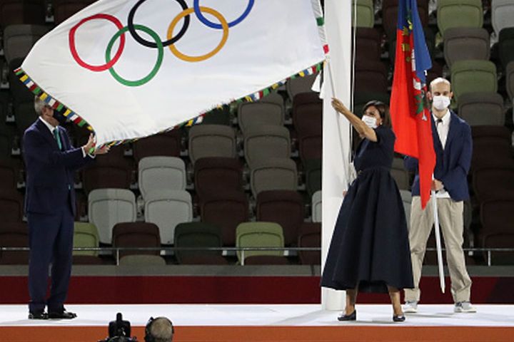 引き継ぎ式にて、五輪旗を振るパリ・イダルゴ市長。
