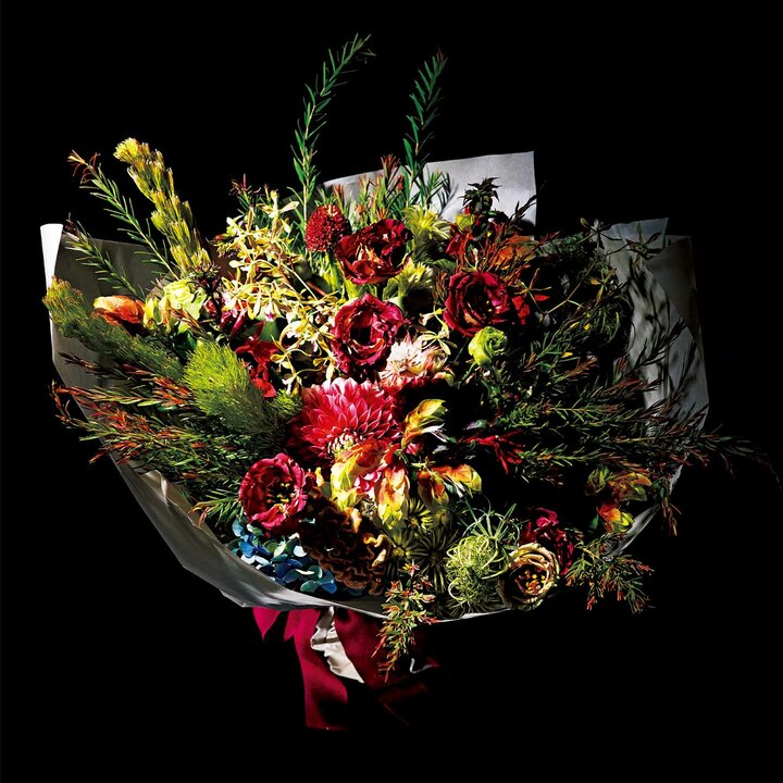 フラワーアーティスト則武潤二さんが率いる「フラワーノリタケ」は、独創的な世界観でファッション業界の女性も注目する名古屋市・栄の人気店。写真は「友人の独立祝い」をテーマに依頼したアレンジブーケだ。鍵となる花材は、蘭の一種であるエンシクリアとふわりと柔らかな表情を作るフィリカ。前者は〝清らかな幸福〟、後者は〝明るさ〟という花言葉がある。「大切な人の明るくこぼれる笑顔を想像しながら、前を向き、未来を見据える姿勢に輝かしい希望を託しました」という。目にする人が思わず元気になる、そんなアレンジメントが素敵だ。ブーケは希望額に応じて製作可。￥10,000［送料込み］（フラワーノリタケ）