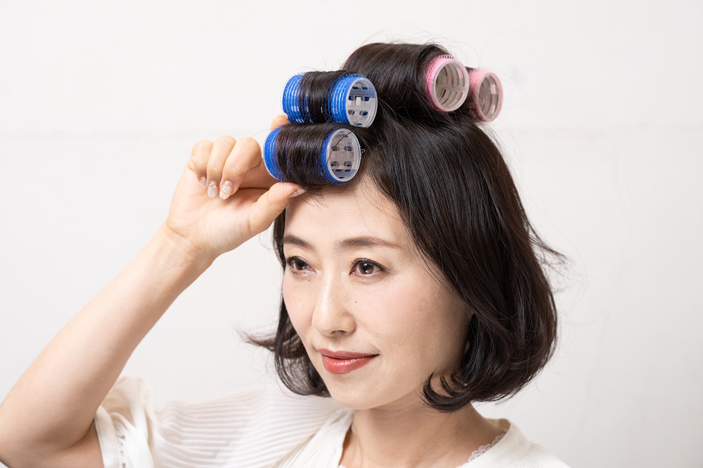 分け目をまたぐように、2層に分けた前髪の上段から順に内巻きにする。