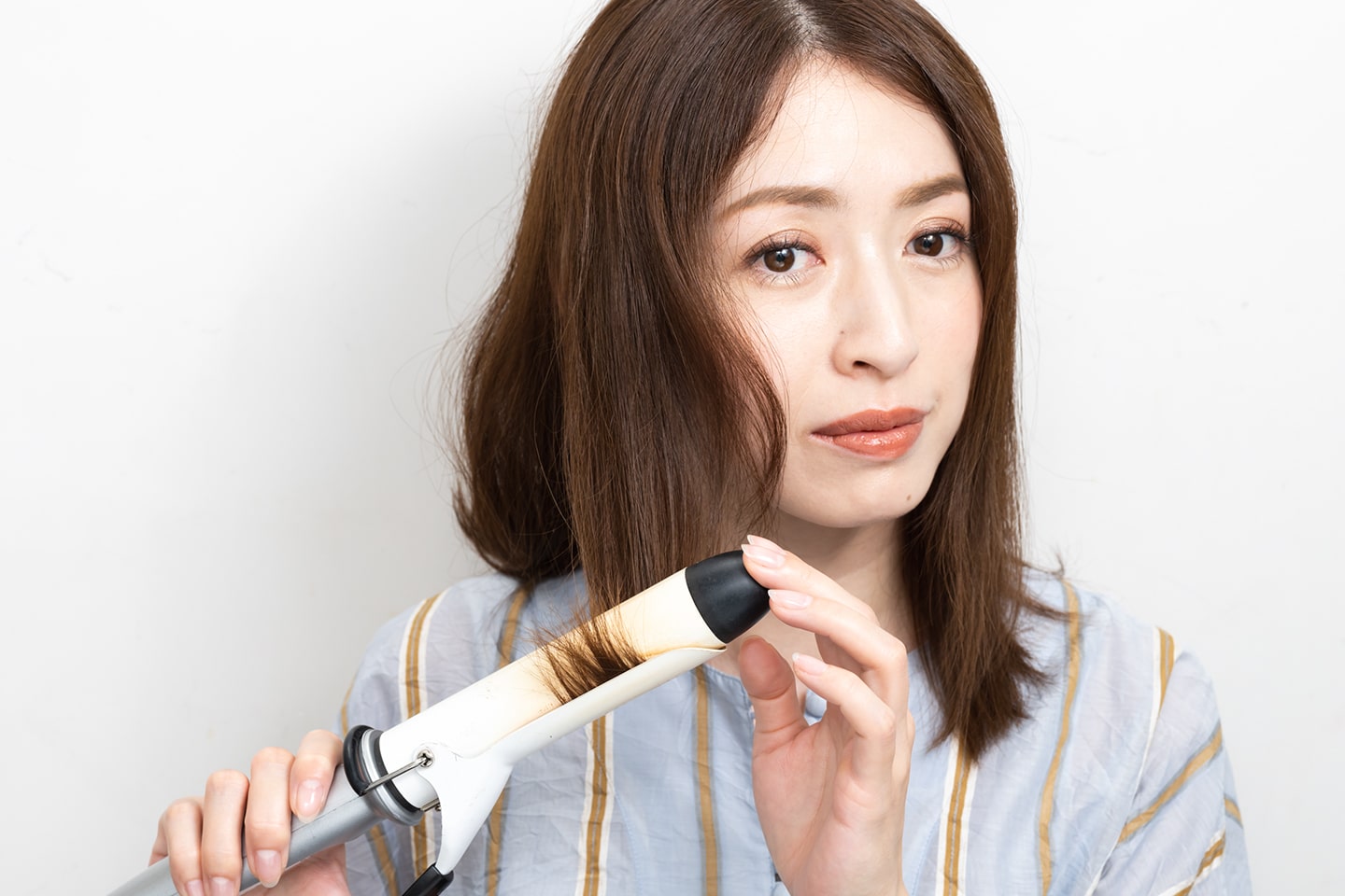 カールアイロンで毛先を外はねに巻く。