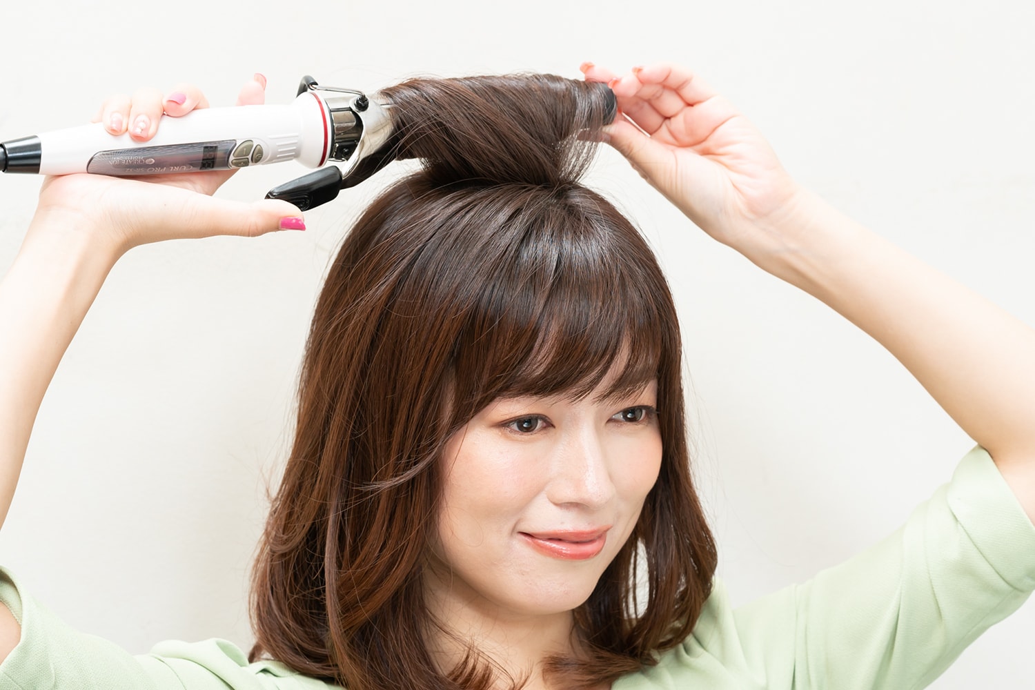 アイロンは32mmを使用。つむじと前髪の間にある毛束をざっくりと取って後頭部に向けて巻く。巻いたらすぐに外して。