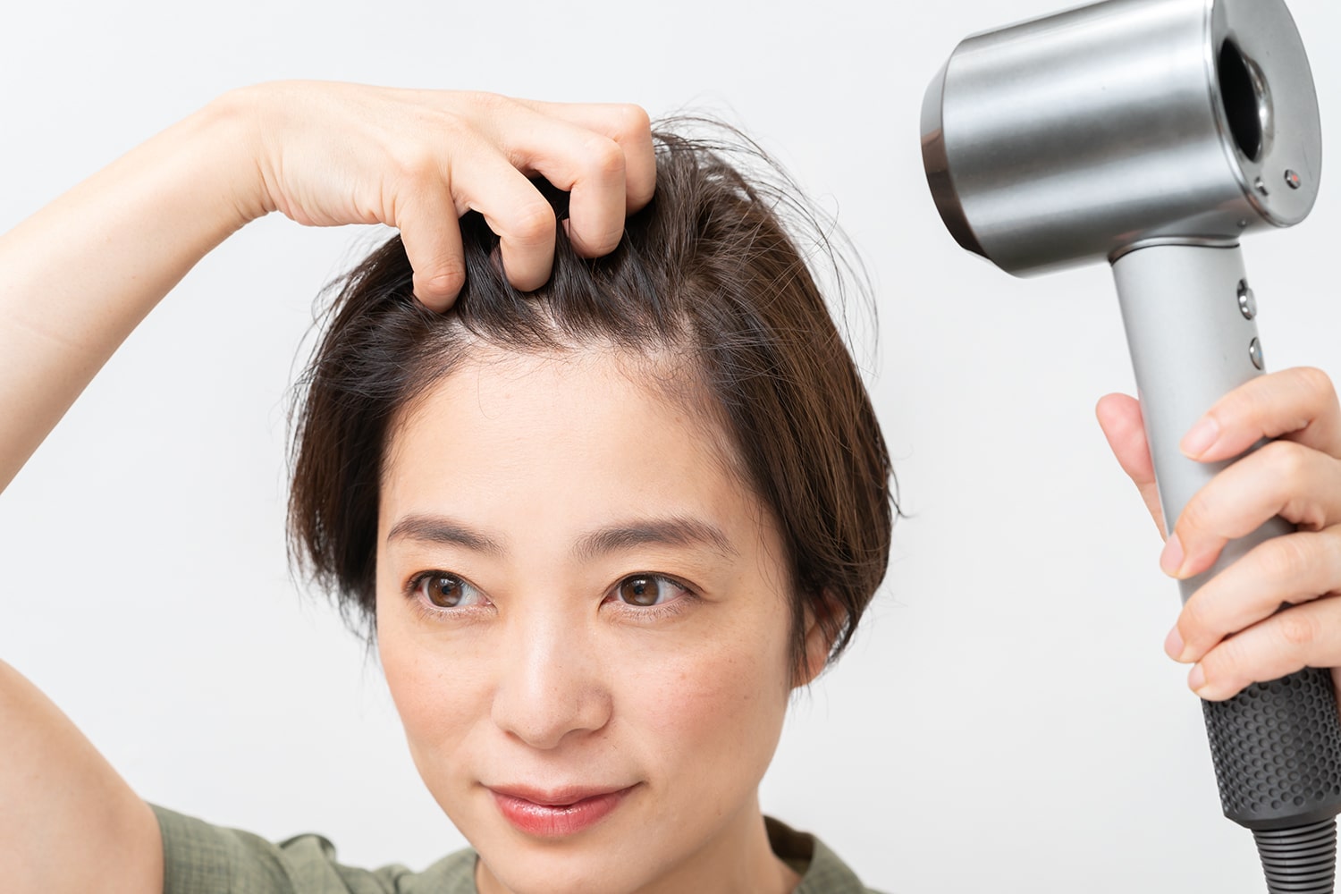 分け目とは逆方向から手ぐしでとかしながら、根元にドライヤーをあてる