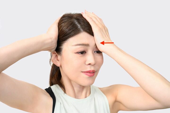 手のひらの下側の付け根で左側の眉骨をプッシュする