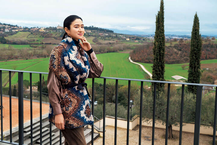 丘の上から平地のほうを見下ろすと緑豊かな牧草地や畑が広がって。この秋、さらに広大な敷地にサッカー場を含む公園が完成。ニットベストは、仕上がりまでにハンドメイドで35時間を要する、まさに職人の高い技術があってこその、芸術品。ニットベスト（リボンベルト付き）￥841,000・カットソー￥63,000・シャツ［参考商品］・パンツ￥474,000（ブルネロ クチネリ ジャパン）