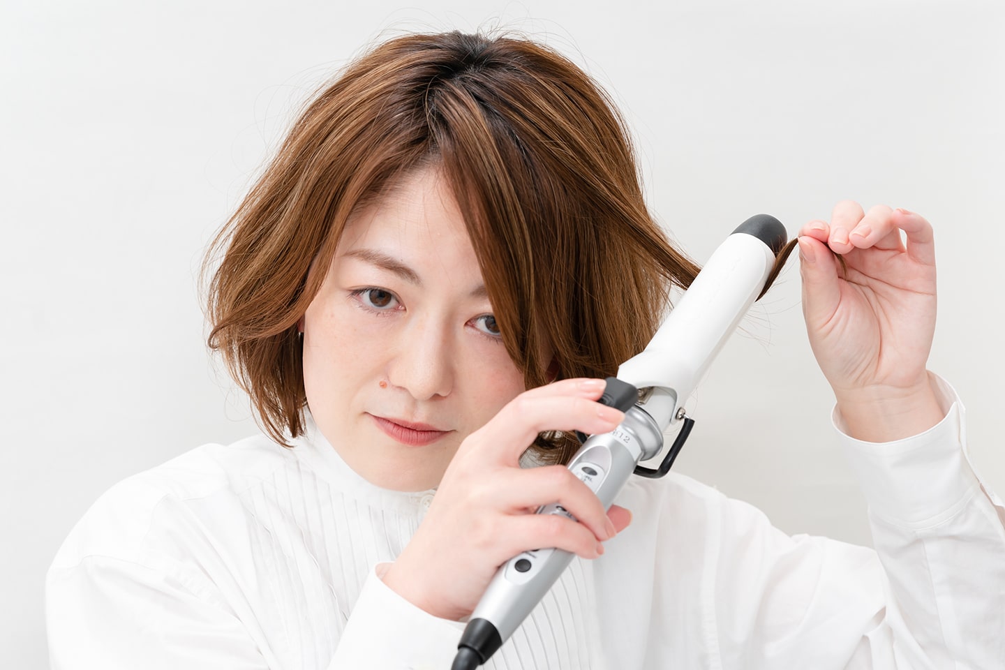 毛束の先端を持ちながら、アイロンを中間あたりに軽く乗せる。