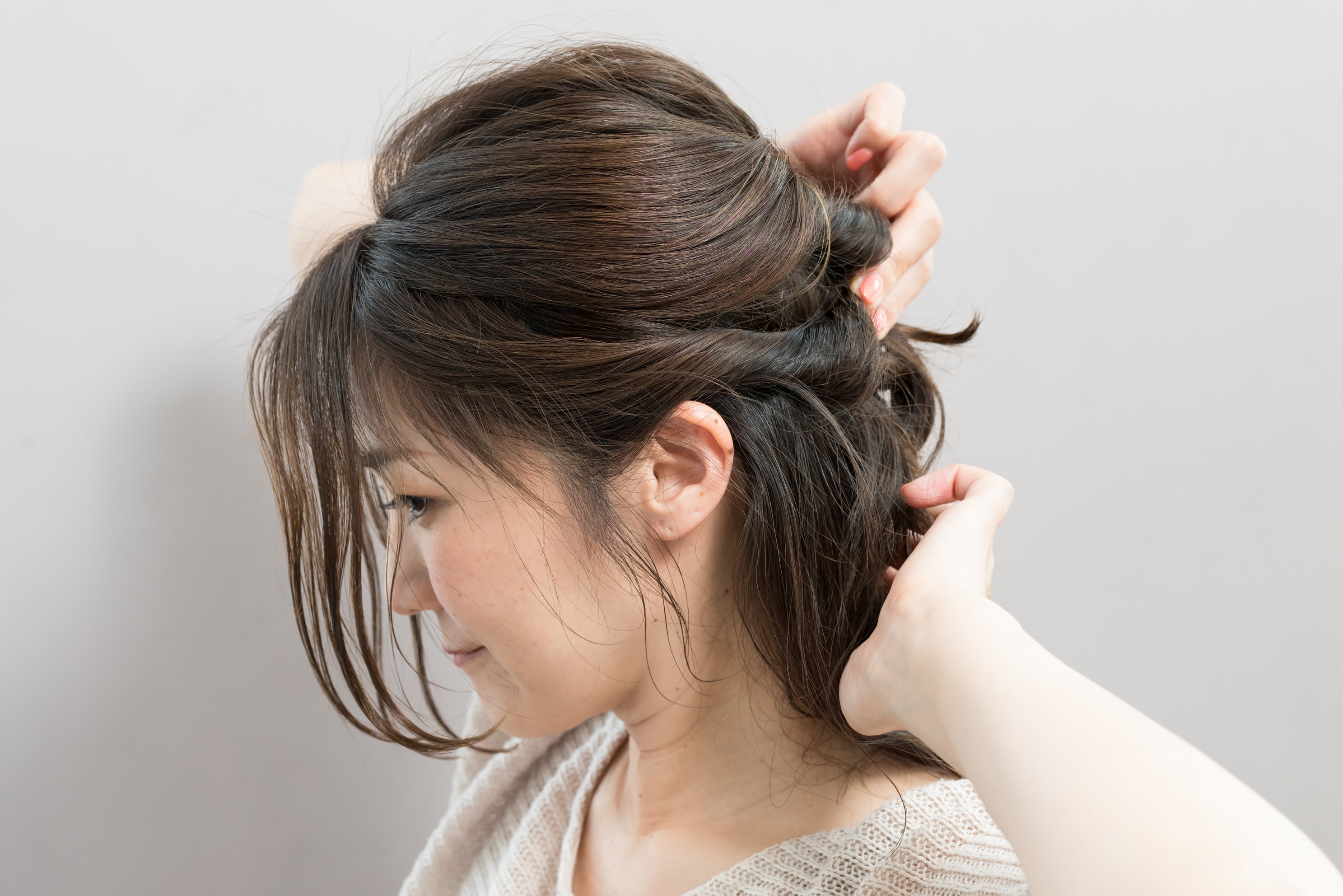 こめかみ付近と耳上の髪をねじりながら後ろへ。