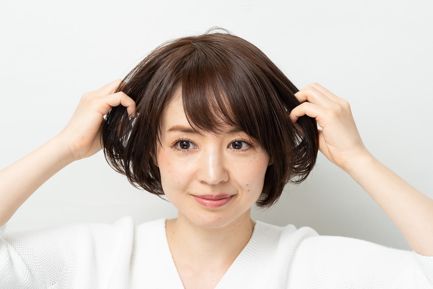 パサつきやすい中間から毛先を手ぐしで整えながらオイルをなじませる。