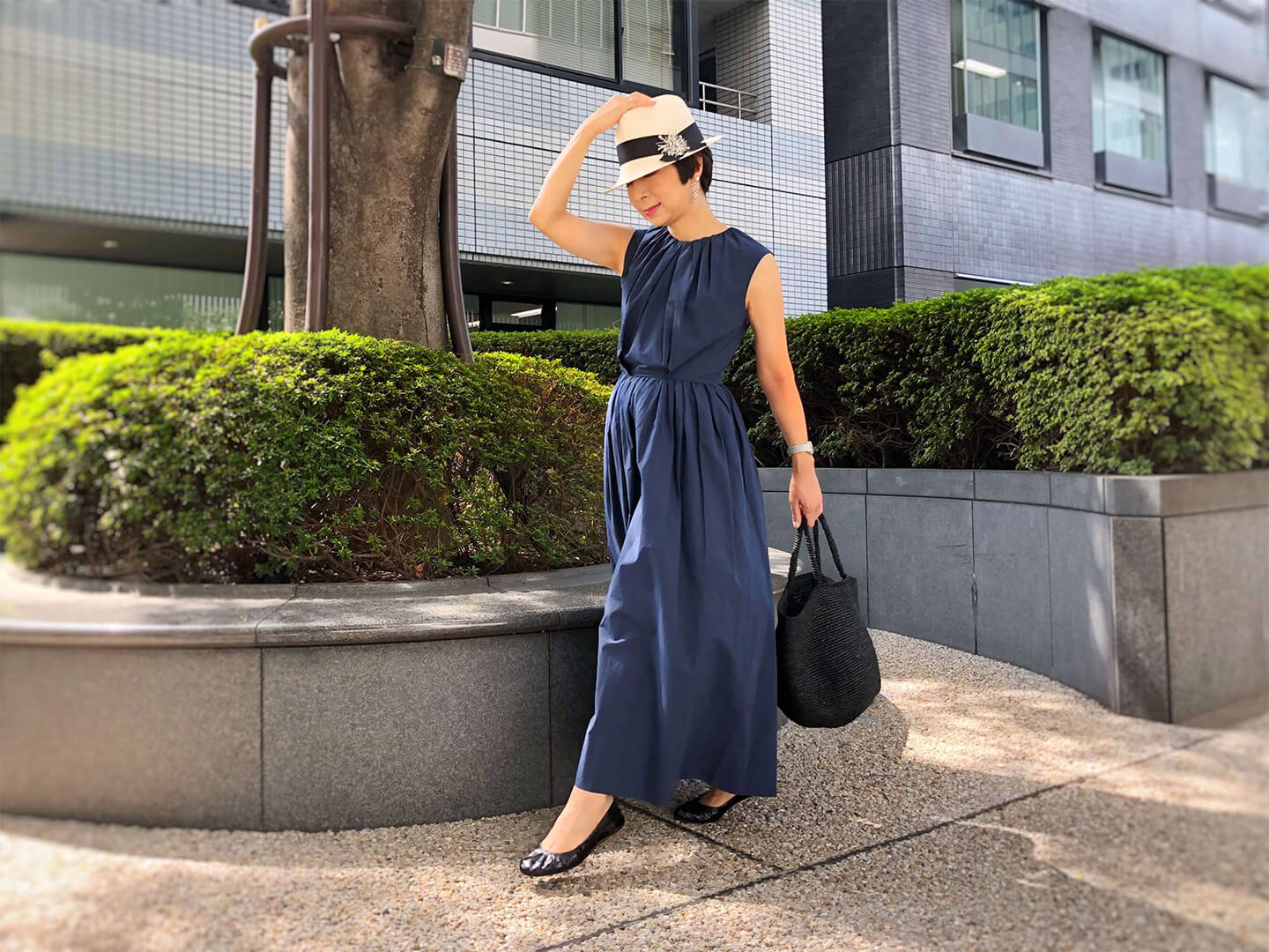 胸元、ウエストにたっぷりとギャザーが入っているので、コットン素材でもしわが気にならないのも魅力。ネイビーも明るめなのが、着映えポイントに。ワンピース/ドゥロワー 帽子/ブルネロ クチネリ バッグ/Sans Arcidet 時計/ベダ&カンバニー