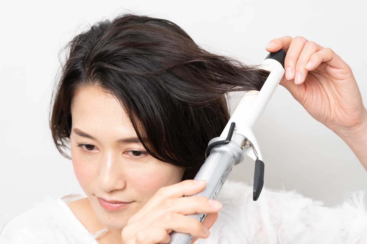 髪表面の毛束をとって毛先を内側にワンカール。コテは26mmを使用。
