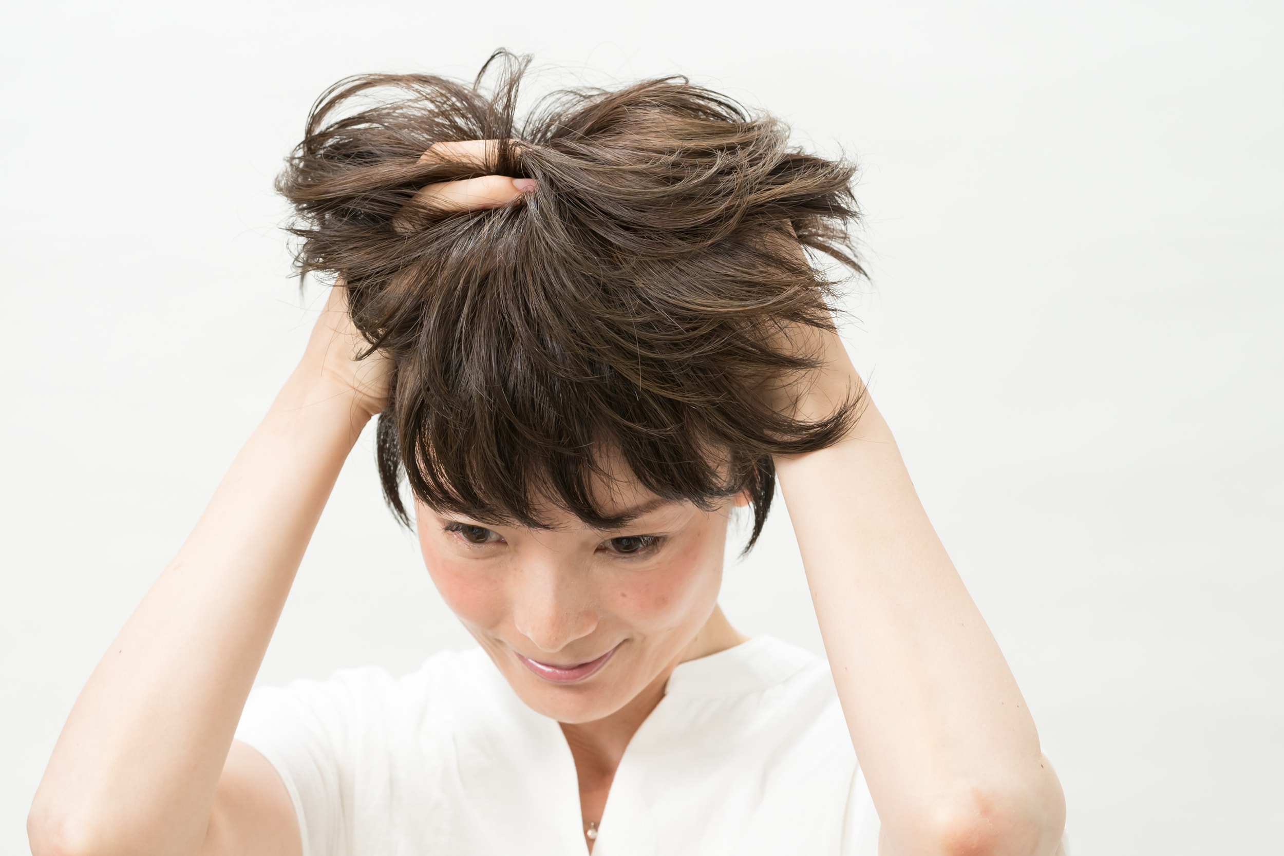 パール粒ふた粒大くらいのワックスを手のひらになじませて、髪の根元から髪全体にもみ込む。